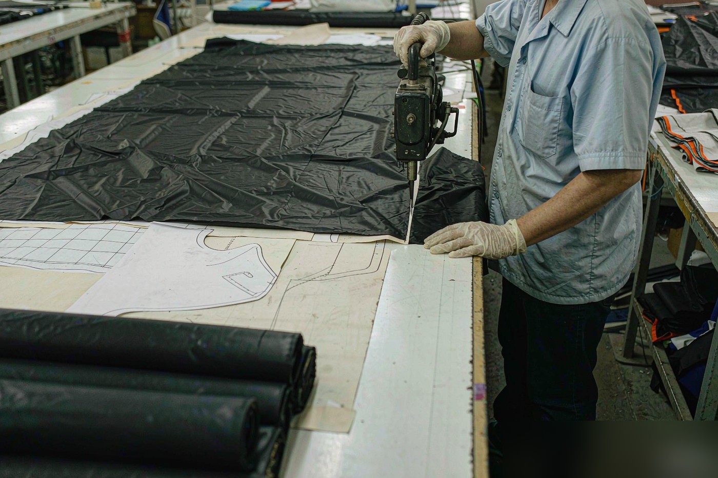 Bag fabric cutting table with layered nylon panels and paper patterns