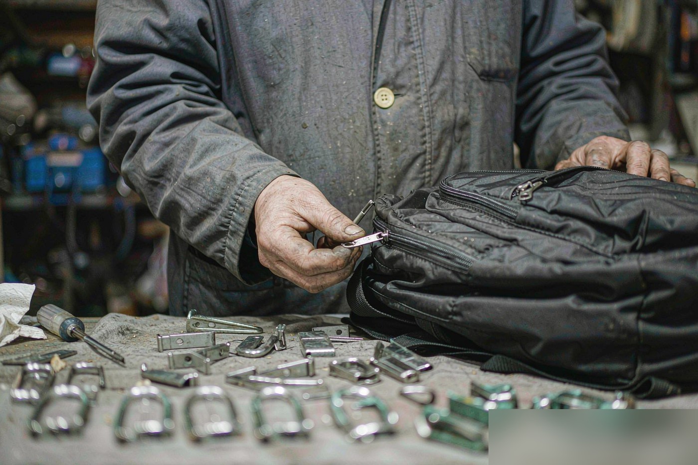 Technician at the workbench setting hardware and inspecting a black nylon backpack